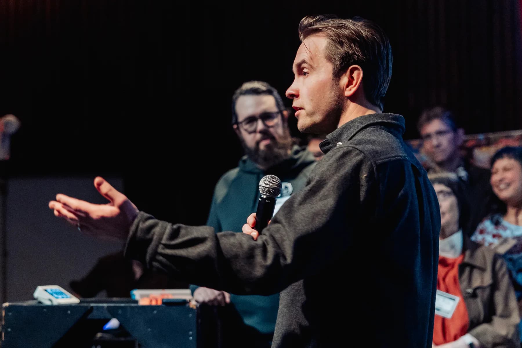 Community member speaking with a microphone in a packed Space Centre auditorium