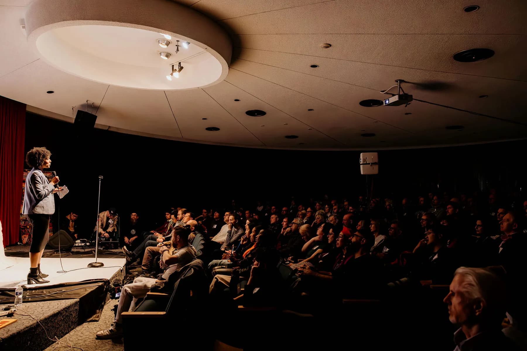 Wide auditorium with a speaker and full room