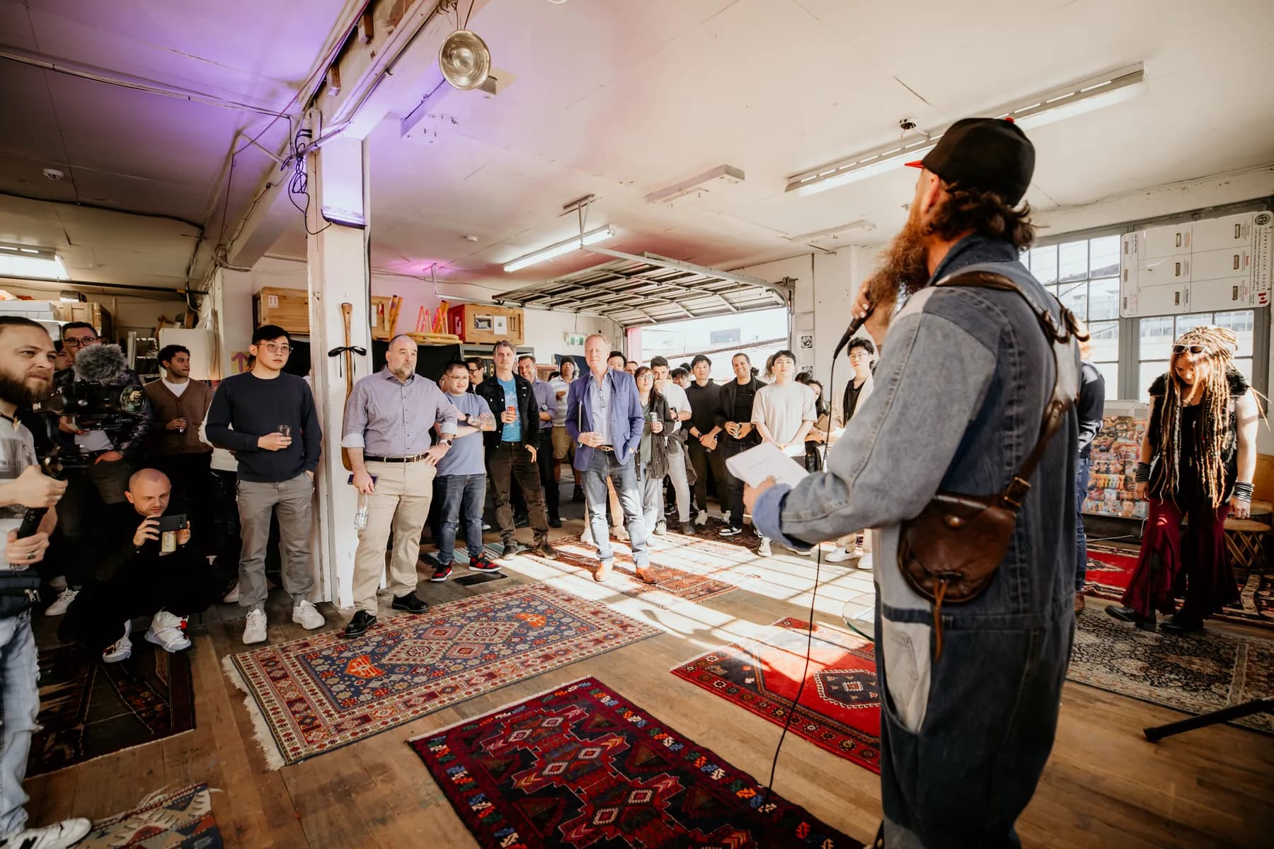Kris facilitating a community workshop in a loft space, addressing a standing crowd