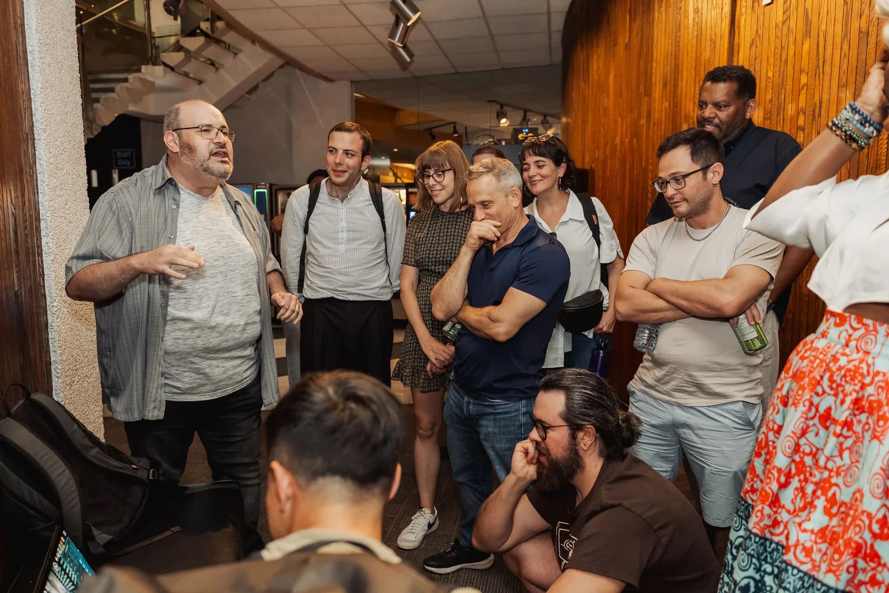 Builders and community members cluster around a laptop during a hands-on demo huddle.