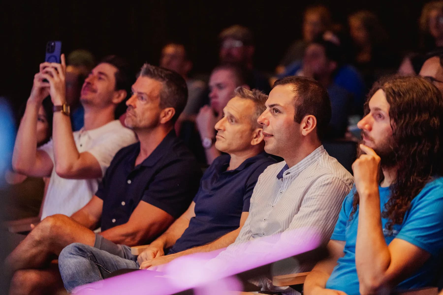 Audience members watch a hackathon presentation from the front row.